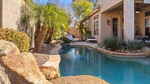 A pool area with a curved design, surrounded by rocks and plants. - New Listing! Charming home in a Great Neighborhood (Peoria)