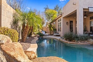 A pool area with a curved design, surrounded by rocks and plants. - New Listing! Charming home in a Great Neighborhood (Peoria)
