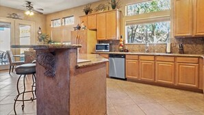 Une cuisine avec des meubles en bois, un plan de travail en granit, un four à micro-ondes encastré et un lave-vaisselle.