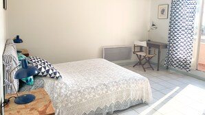 A bedroom with a bed, a desk, a chair, a lamp, and a window with curtains. - 10 pax, Family friendly, 2 mins walk to the beach, sea view. (Hyères)