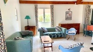 A living room with patterned sofas, a wooden coffee table, a rocking chair, and a wooden cabinet. - 10 pax, Family friendly, 2 mins walk to the beach, sea view. (Hyères)