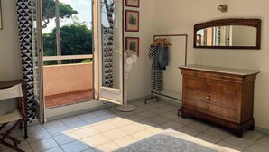 A room with a wooden dresser, a mirror, a fan, and a door leading to a balcony. - 10 pax, Family friendly, 2 mins walk to the beach, sea view. (Hyères)