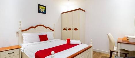 Un dormitorio con cama, armario, escritorio y silla.