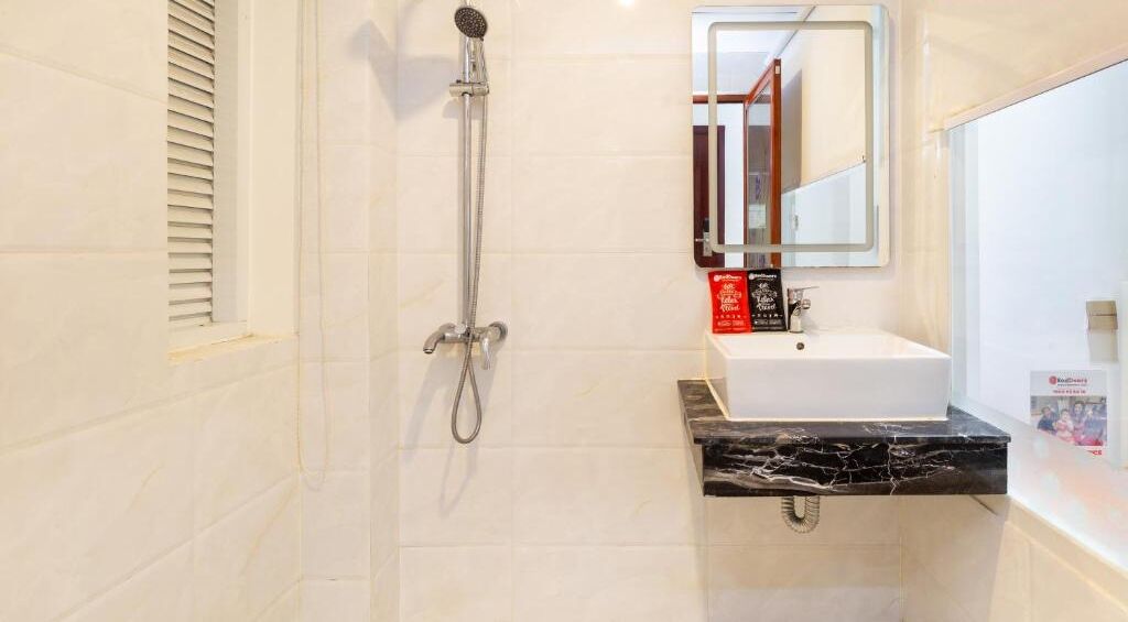 A bathroom with a white sink, a handheld showerhead, and a mirror above the sink.