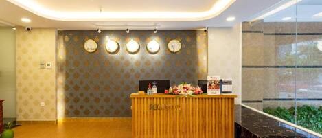 A reception area with a wooden reception desk, a wall clock, and a 'plus' sign indicating additional services.