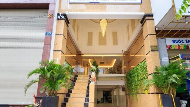 A hotel entrance with a staircase leading to the lobby, potted plants, and a closed shutter door. - Spring Airport Hotel (Ho Chi Minh City)