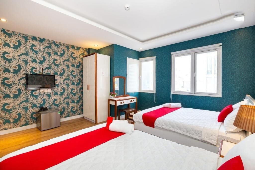 Habitación de hotel con dos camas, un escritorio, un espejo y un televisor.