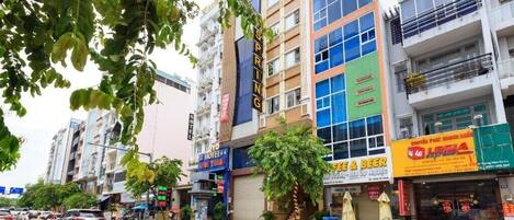 A multi-story building with various businesses on the ground floor, including a hotel and a beer shop.