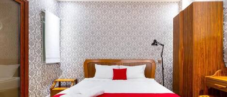 A neatly made bed with a red and white bedspread, a wooden headboard, and a white towel on the side.