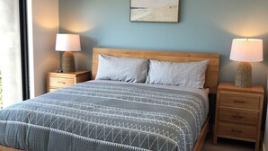 Una camera da letto con un letto di legno, due comodini, una lampada a parete e una finestra.