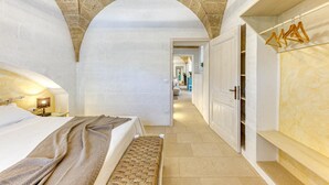 Un couloir étroit mène à une chambre qui contient un lit, un banc et une armoire.