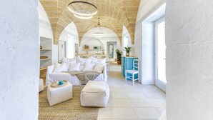 Une pièce spacieuse avec un grand lit, un coin salon avec un fauteuil bleu et une cuisine à l’arrière-plan.