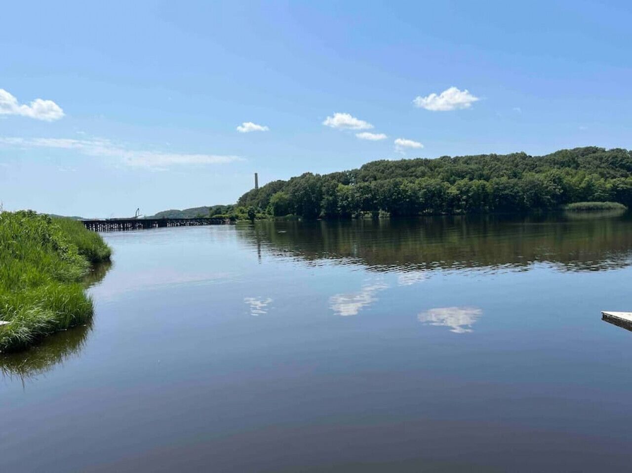 Une rivière paisible, avec un pont et une végétation luxuriante sur ses rives.
