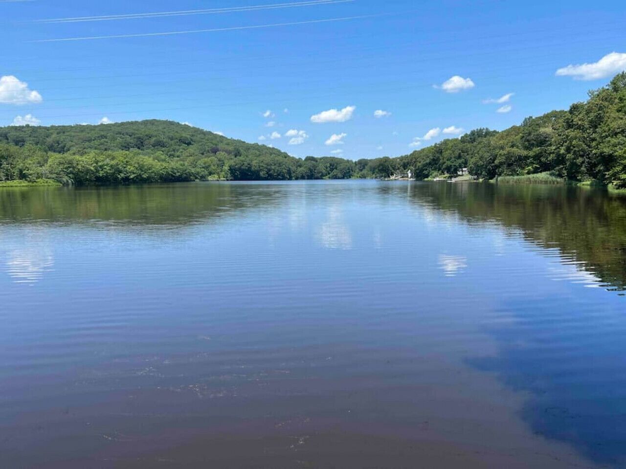 A calm lake with a forested hill in the background.