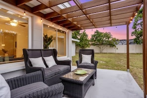 An outdoor patio with wicker furniture and a glass door leading to a room. - Tasteful Home, Big Yard, Central, 2 miles to Beach (Sarasota)
