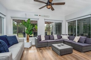 A modern living room with a sectional sofa, a coffee table, and a ceiling fan. - Tasteful Home, Big Yard, Central, 2 miles to Beach (Sarasota)