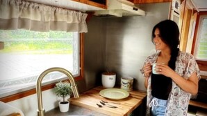 A compact kitchen with a sink, a window, and a small potted plant.