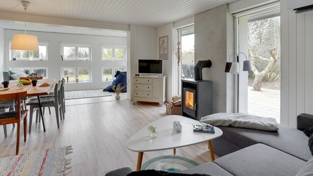 Una sala de estar moderna con chimenea, un comedor con mesa y sillas de madera, y ventanas amplias que ofrecen luz natural.