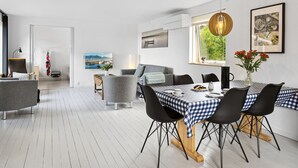 Un comedor moderno con mantel a cuadros, sillas negras y una lámpara colgante.