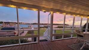 A wooden deck with a view of a lake and a boat dock. - Private cottage at the end of the road with hot tub, swim mat, kayaks, and a your private dock, 3 miles to the beach. (Cedar Point)