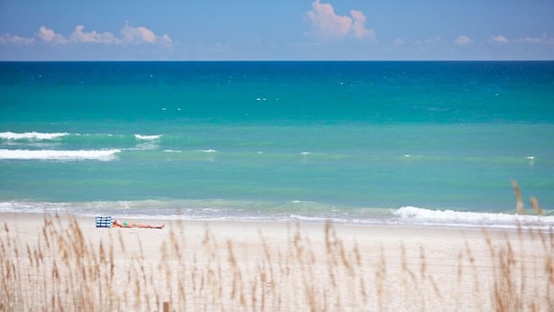A beach with clear turquoise water and a person lying on a beach towel. - Private cottage at the end of the road with hot tub, swim mat, kayaks, and a your private dock, 3 miles to the beach. (Cedar Point)