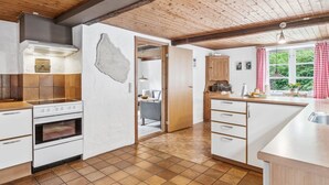 A modern kitchen with white cabinets, a wooden ceiling, and a large window with curtains. - "Rina" - 250m from the sea by Interhome (Hasle)