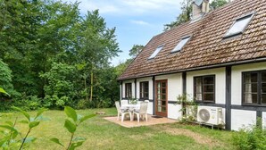 A house with a tiled roof, a small patio with a table and chairs, and a garden with trees and grass. - "Rina" - 250m from the sea by Interhome (Hasle)