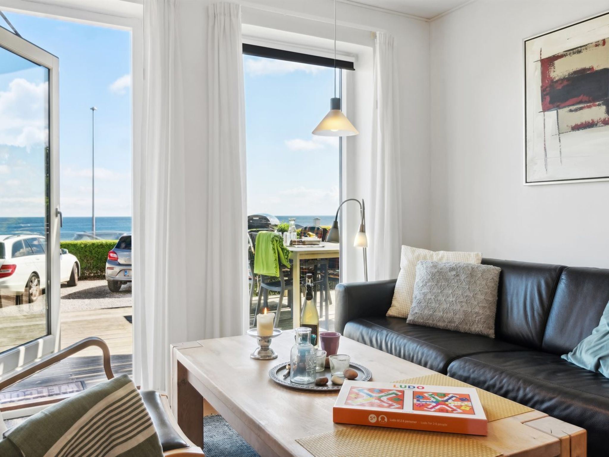 Ein modernes Wohnzimmer mit Couchtisch aus Holz, einer schwarzen Ledersofa und Meerblick durch große Fenster.