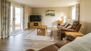 Een woonkamer met een bank, een salontafel, een televisie en een lamp.
