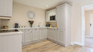 Een moderne keuken met witte kasten, een roestvrijstalen magnetron en een houten vloer.