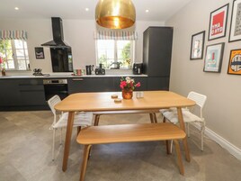 Una cocina moderna con una mesa de comedor de madera, sillas blancas y un banco.
