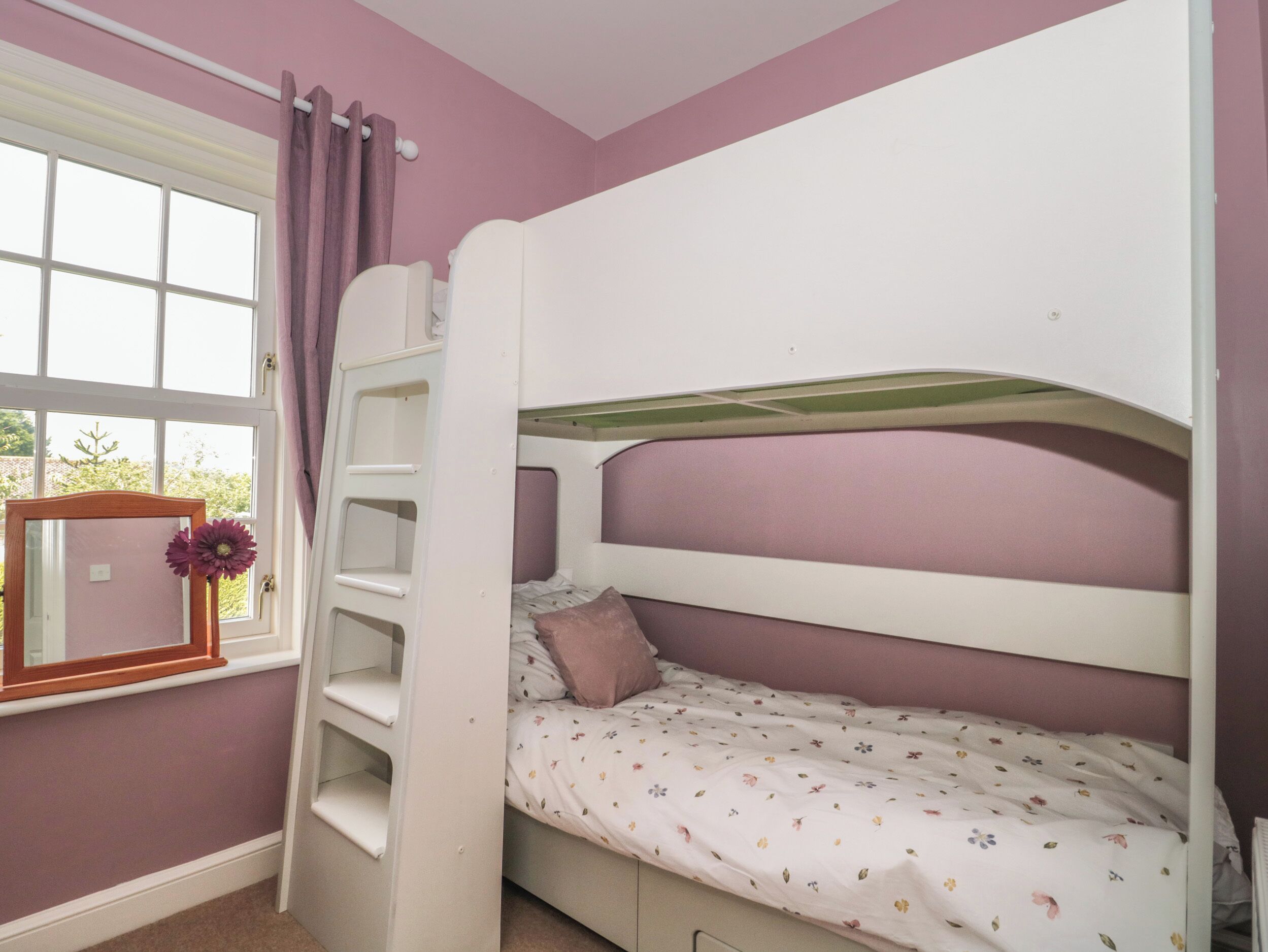 A bunk bed with a window and a mirror.