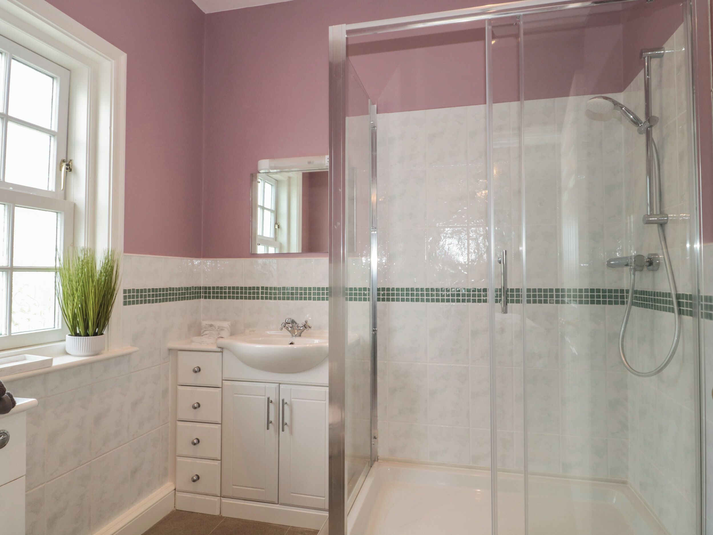 Une salle de bain avec une douche à parois de verre, un lavabo et un meuble de rangement.