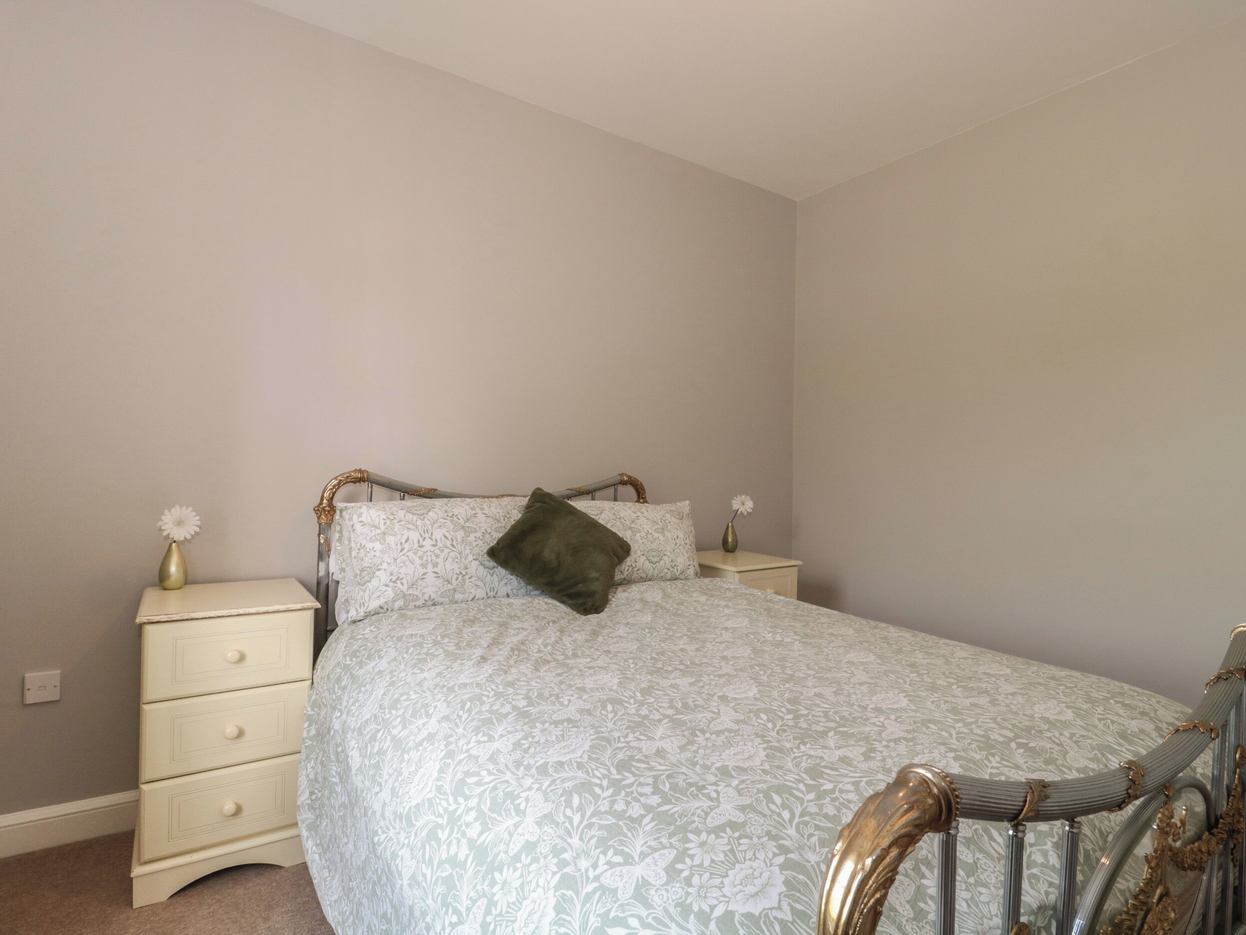 Un dormitorio ordenado con una cama, una mesita de noche y una mesilla.