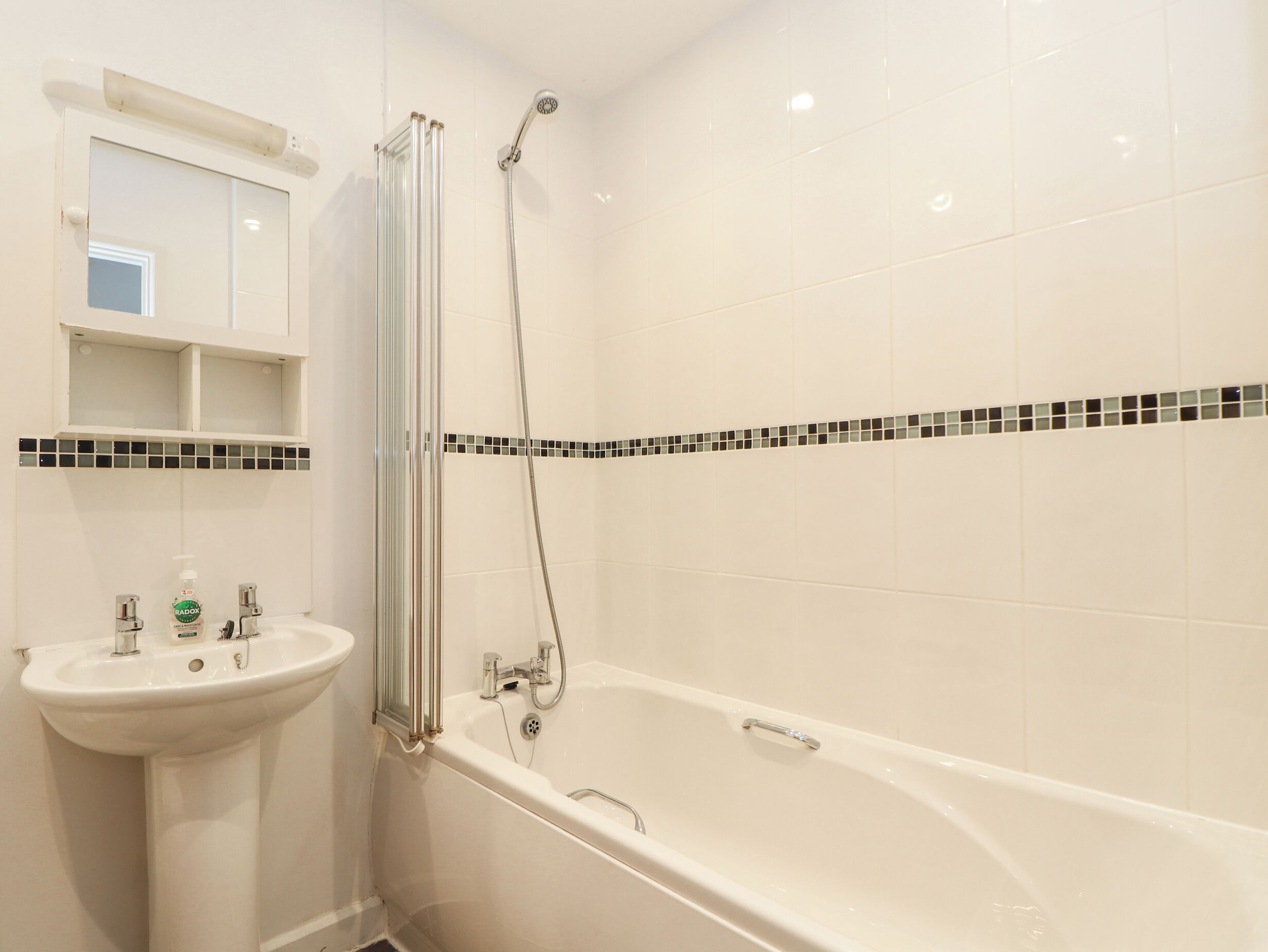 Un bagno con lavandino bianco, vasca da bagno e box doccia.