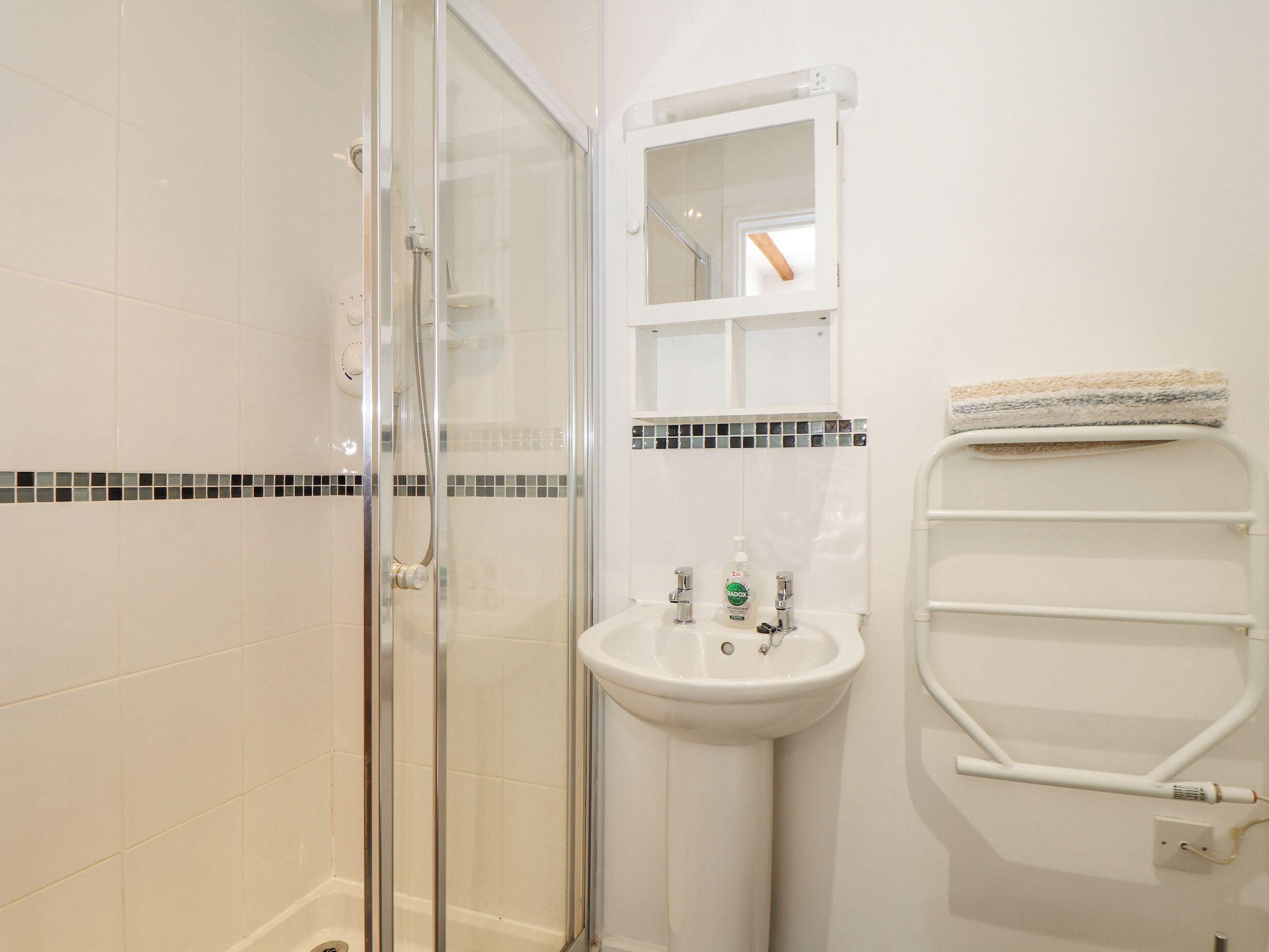 Ein Badezimmer mit Duschkabine, Standwaschbecken und Handtuchhalter.