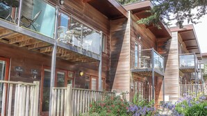 Un edificio de madera con varios balcones, mobiliario exterior y una valla de madera.