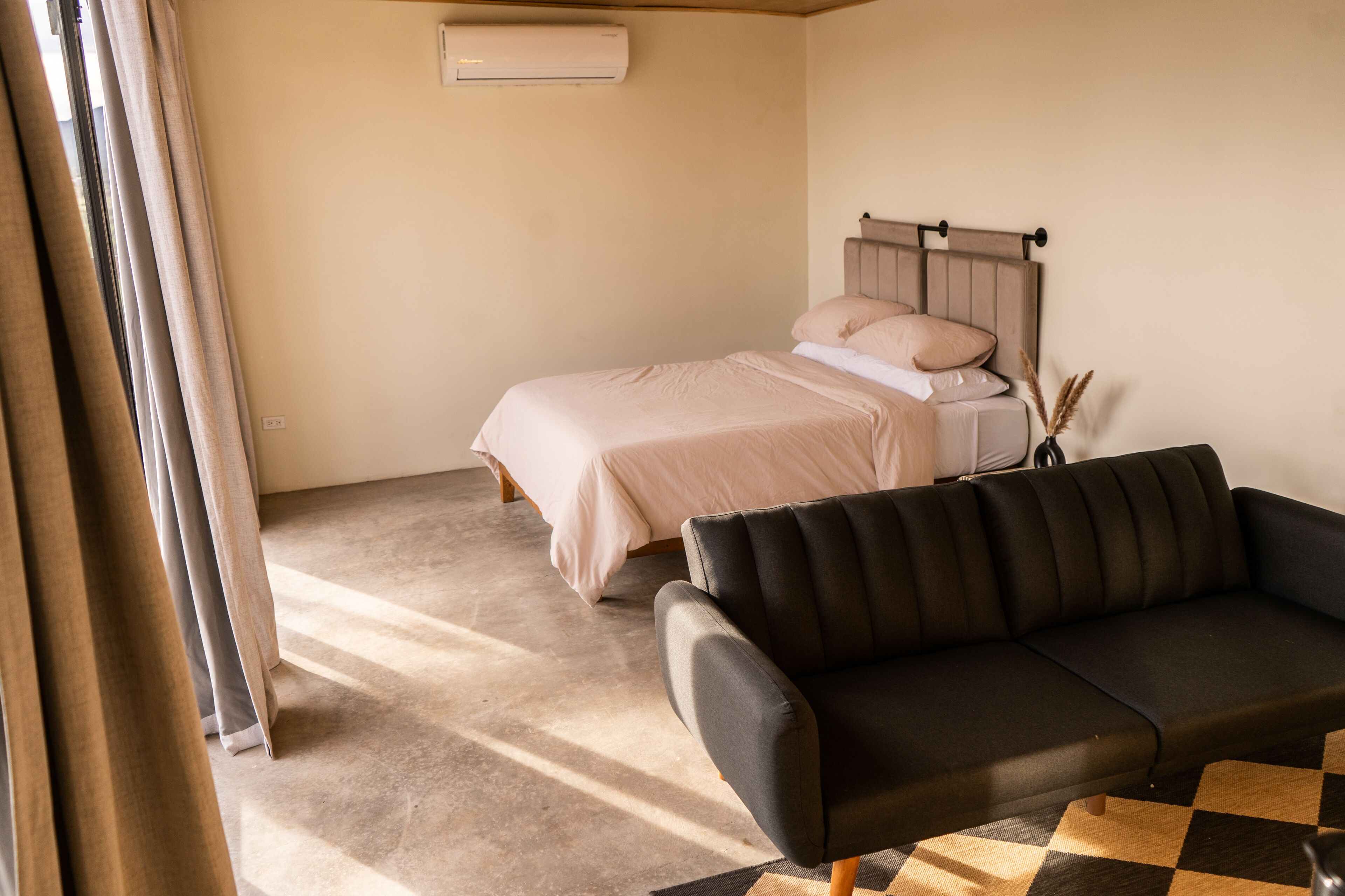Ein Schlafzimmer mit einem Bett, einer schwarzen Couch und einem Schachbrettteppich.