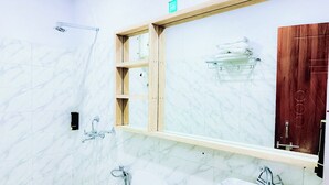Un baño moderno con paredes de mármol, un mueble de tocador de madera, un espejo grande y una zona de ducha.