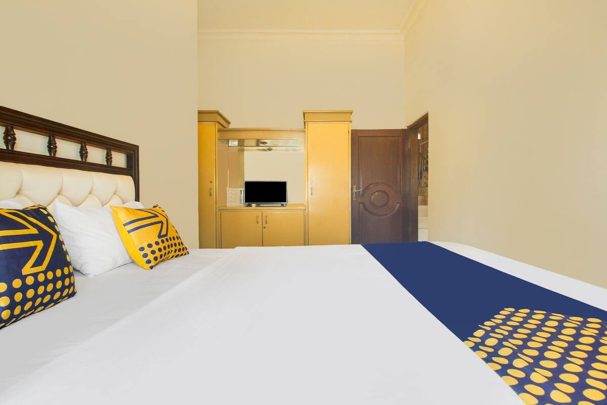 Una habitación de hotel con cama, armario, televisor y puerta.