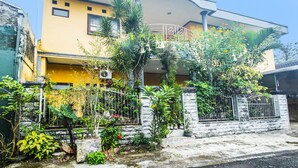 A two-story building with a balcony, surrounded by various plants and a gated entrance. - SPOT ON 91620 Skypiea Guest House (Tasikmalaya)
