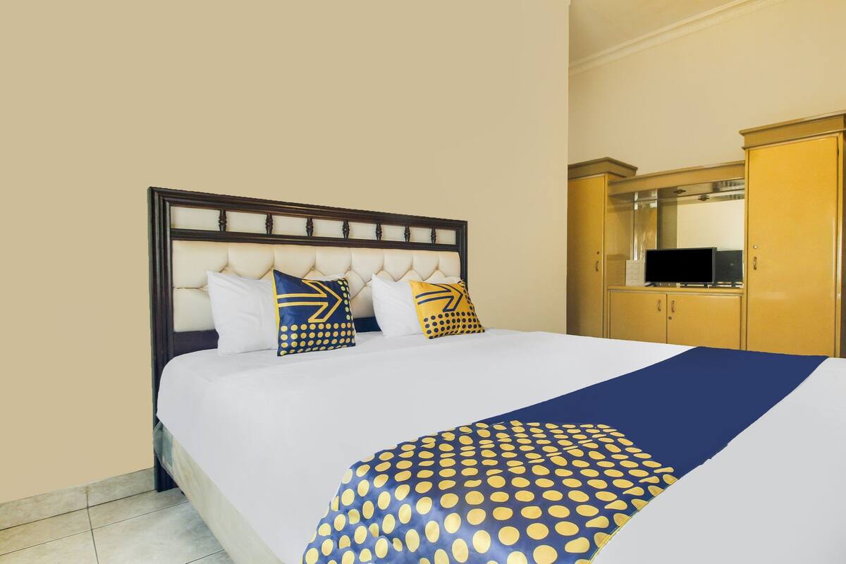 Una habitación de hotel con una cama grande, un cabecero de madera y un armario.