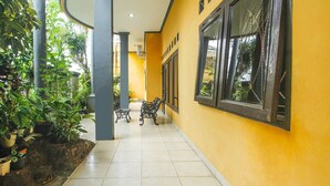 A corridor with tiled flooring, potted plants, and two black metal benches. - SPOT ON 91620 Skypiea Guest House (Tasikmalaya)