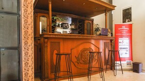 A reception area with a wooden counter, a reception desk, and three bar stools. - SPOT ON 91620 Skypiea Guest House (Tasikmalaya)