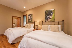 A hotel room with two beds, a wooden floor, a door, and a window with blinds. - Maple Cottage in Sutton Knob (Pisgah Forest)