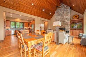 A spacious kitchen with wooden cabinets, a stone fireplace, and a dining area with a wooden table and chairs.
