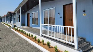 Une rangée de bâtiments bleus, dotés de balcons blancs et de portes numérotées, ce qui laisse supposer qu’il s’agit d’un hôtel ou d’un complexe touristique.