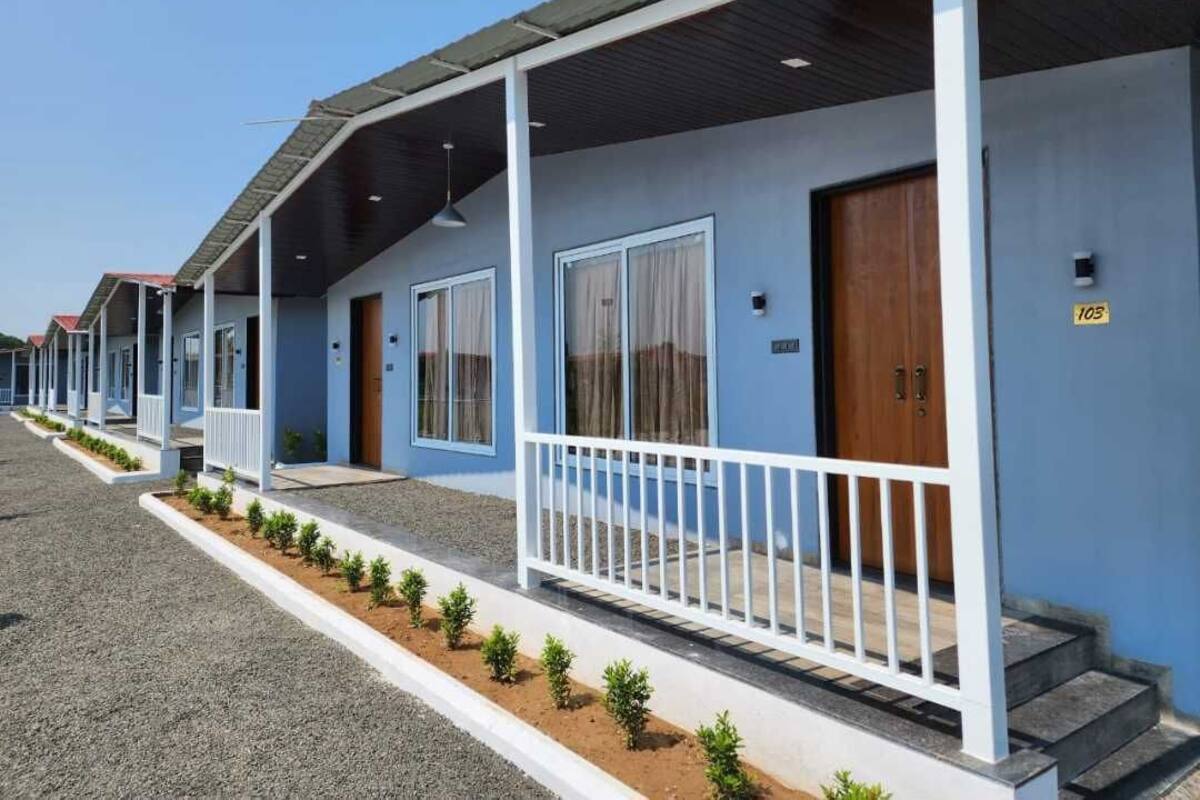 Eine Reihe blauer Gebäude mit weißen Geländern und nummerierten Türen, die an ein Hotel oder Resort erinnern.