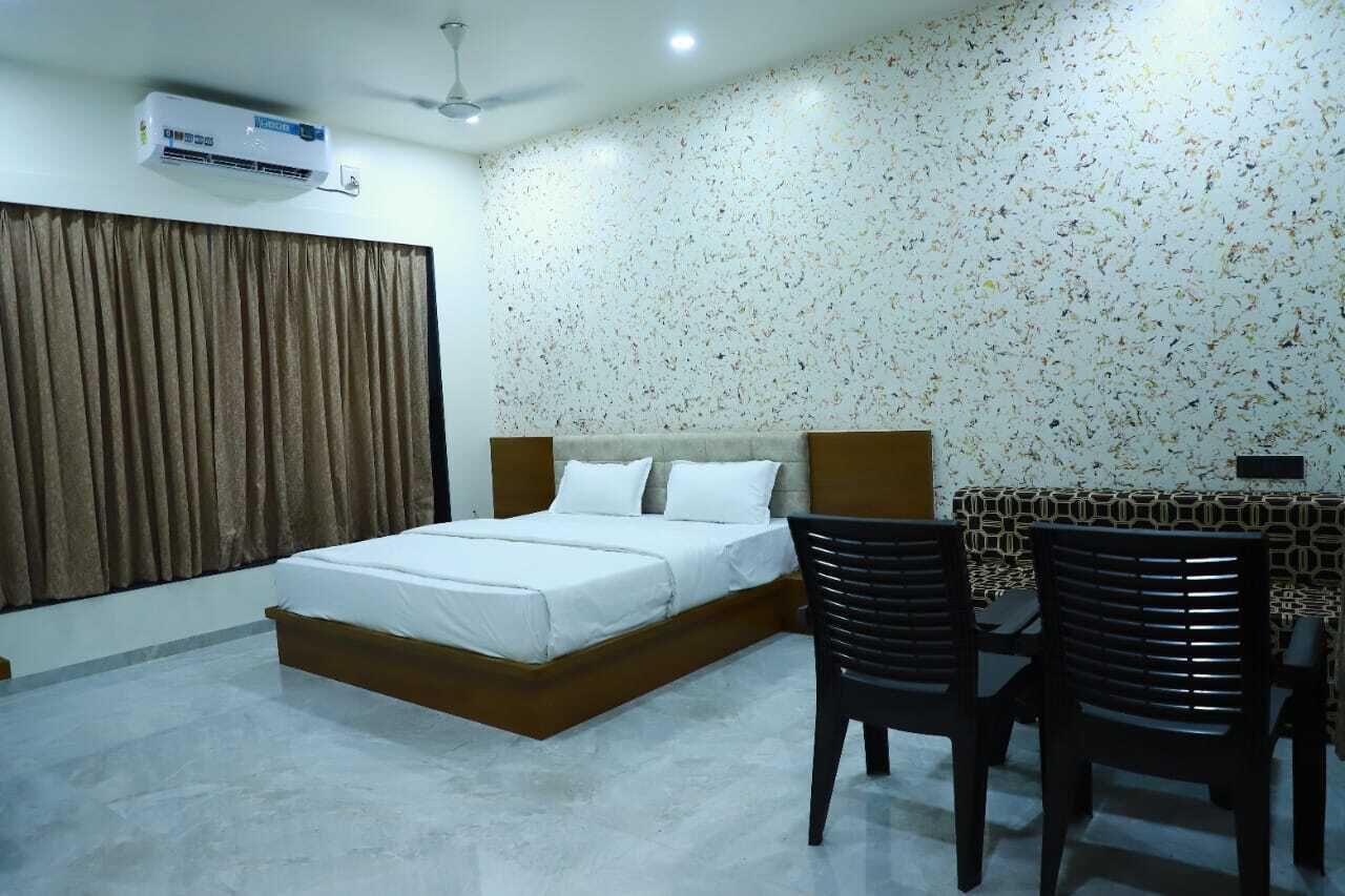 A bedroom with a bed, a desk, and chairs.