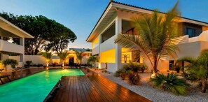 Un complexe hôtelier moderne doté d’une piscine, d’une terrasse en bois et d’un aménagement paysager de style tropical.